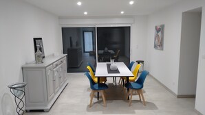 A dining area with a white table, blue and yellow chairs, a white cabinet, and a glass cabinet.