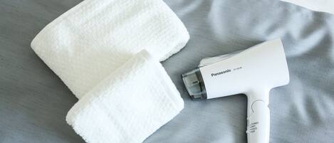 Une serviette blanche et un sèche-cheveux Panasonic sur une surface en tissu gris.