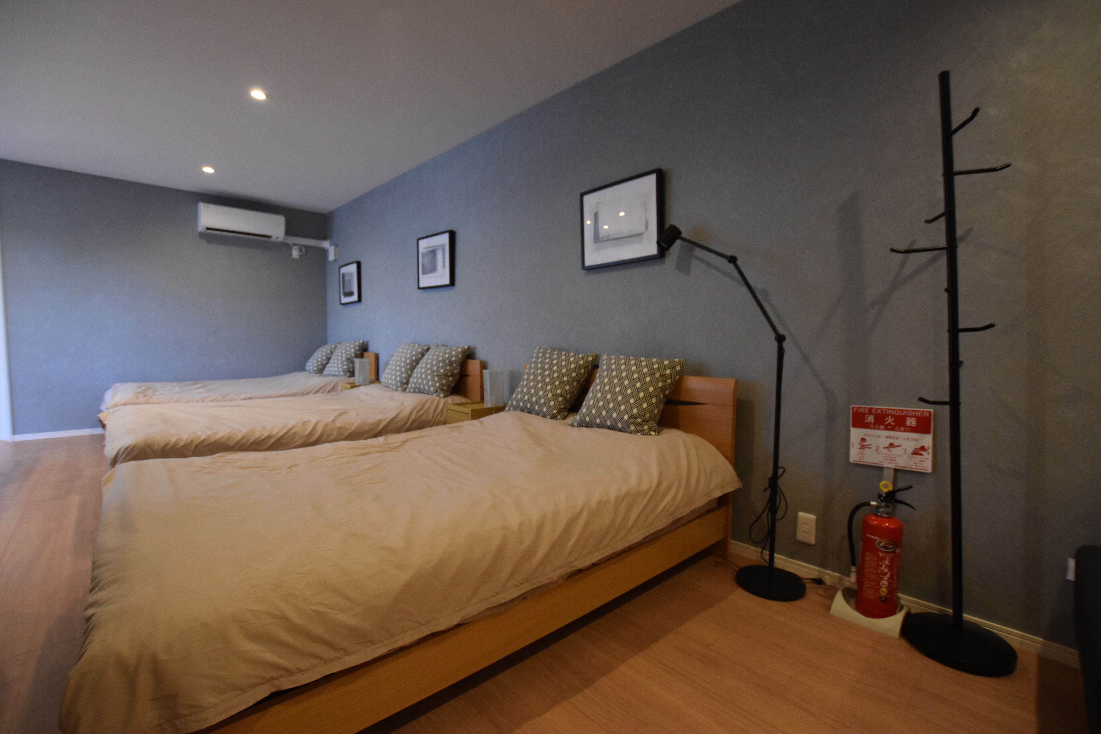 Habitación de hotel con dos camas, un extintor y un aire acondicionado instalado en la pared.