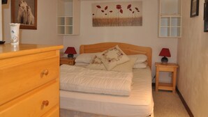 Un dormitorio con una cama de madera, dos mesitas de noche con lámparas, un aparador y un cuadro en la pared.