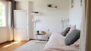 A bedroom with a bed, bedside tables, a small table with a plant, and a window with curtains. - Typical house with enclosed garden in the heart of Cotentin (Saint-Jean-de-la-Rivière)