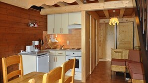 En inredning med träpanel, ett kök, en matplats och en mysig sittgrupp.