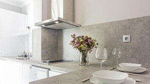 Eine moderne Küche mit Marmorarbeitsplatte, integriertem Geschirrspüler und Spüle aus Edelstahl. Auf der Arbeitsplatte stehen eine Vase mit Blumen und zwei Weingläser.