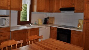 Une cuisine équipée de meubles en bois, d’un four à micro-ondes, d’un évier, d’une bouilloire et d’un lave-vaisselle.