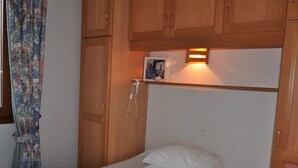 Une chambre avec des armoires en bois, un lit avec une literie blanche et une table de chevet avec une lampe.