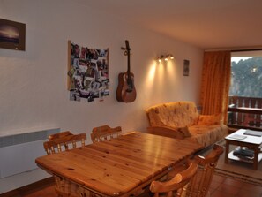 Un comedor con una mesa y sillas de madera, una guitarra y una pared decorada con un collage de fotos.