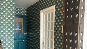 A hallway with a teal door, a white door, and a black door with circular cutouts. There is a sign on the teal door that reads "KEEP CALM AND DRINK HAMPANQUE." - La fine bulle! (Épernay)