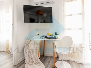 A modern dining area with a TV mounted on the wall, a table set with plates, glasses, and a small plant. - Renovated apartment with balcony, Wi-Fi and air conditioning in Malaga (Málaga)