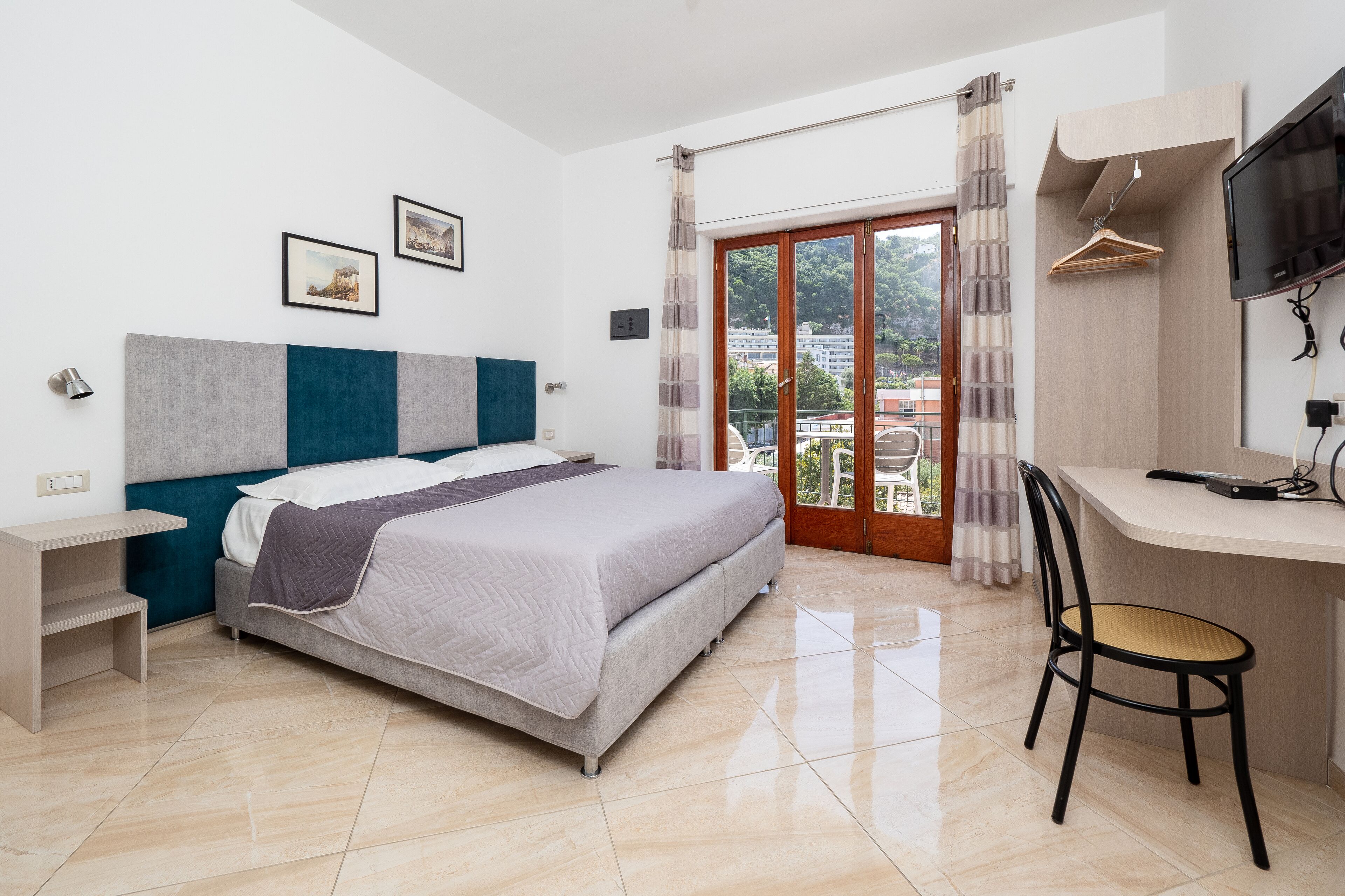 Un dormitorio moderno con cama, escritorio, silla y televisor.
