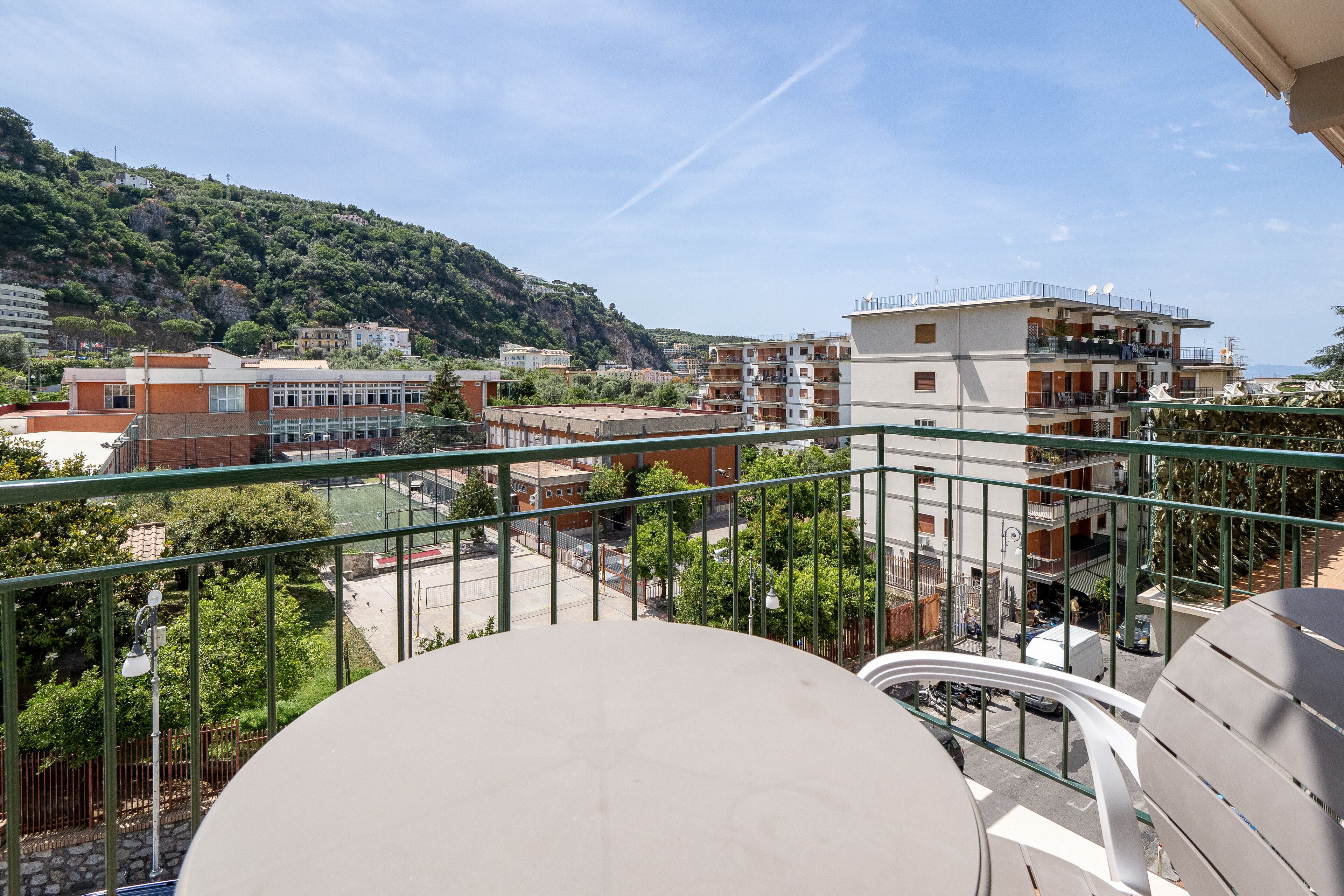 Ein Balkon mit Blick auf eine Hügelkulisse, Gebäude und eine Straße.