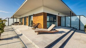 A modern house with a covered patio, outdoor seating, and a staircase leading to the entrance.