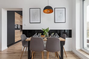 Un comedor moderno con una mesa de madera, cuatro sillas grises y dos cuadros enmarcados arriba.