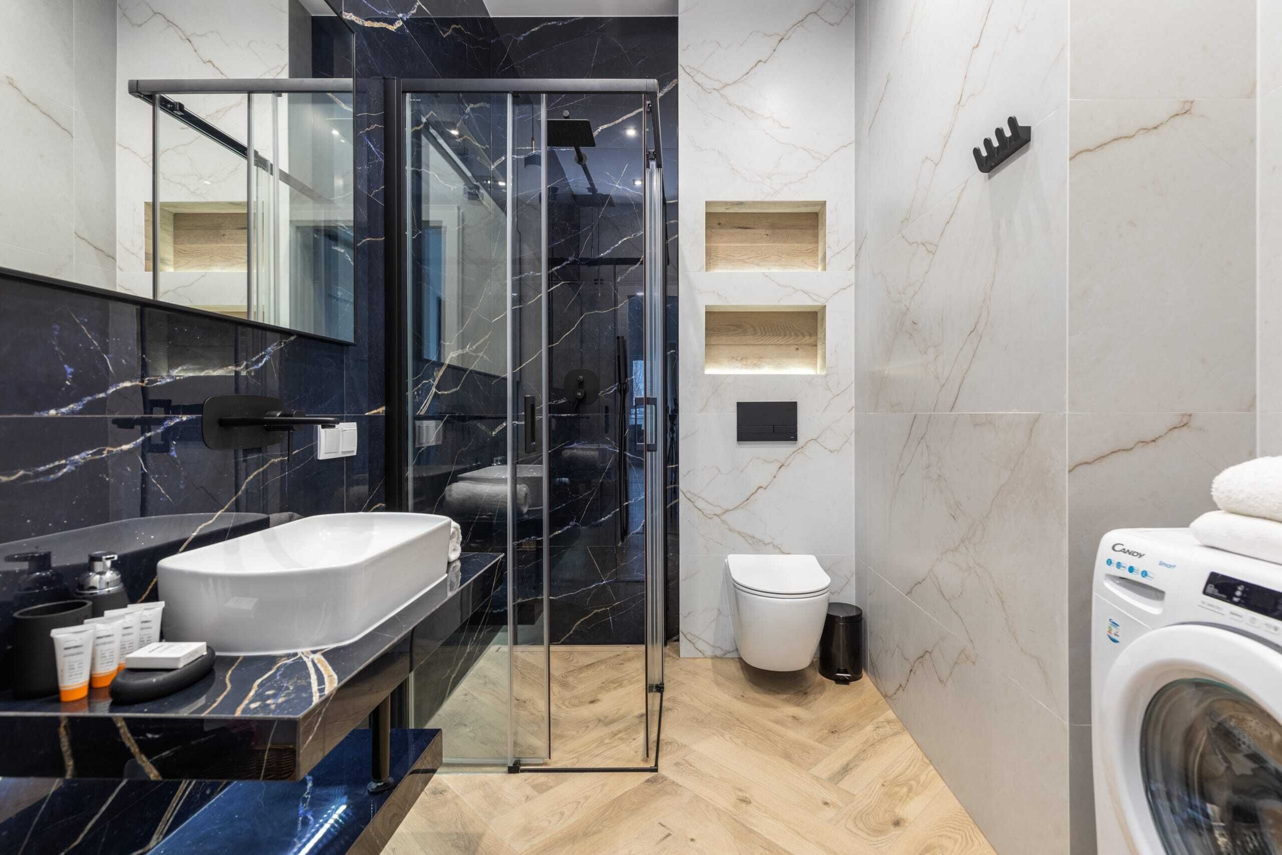 Un baño moderno con ducha de vidrio, lavabo, inodoro y lavadora.