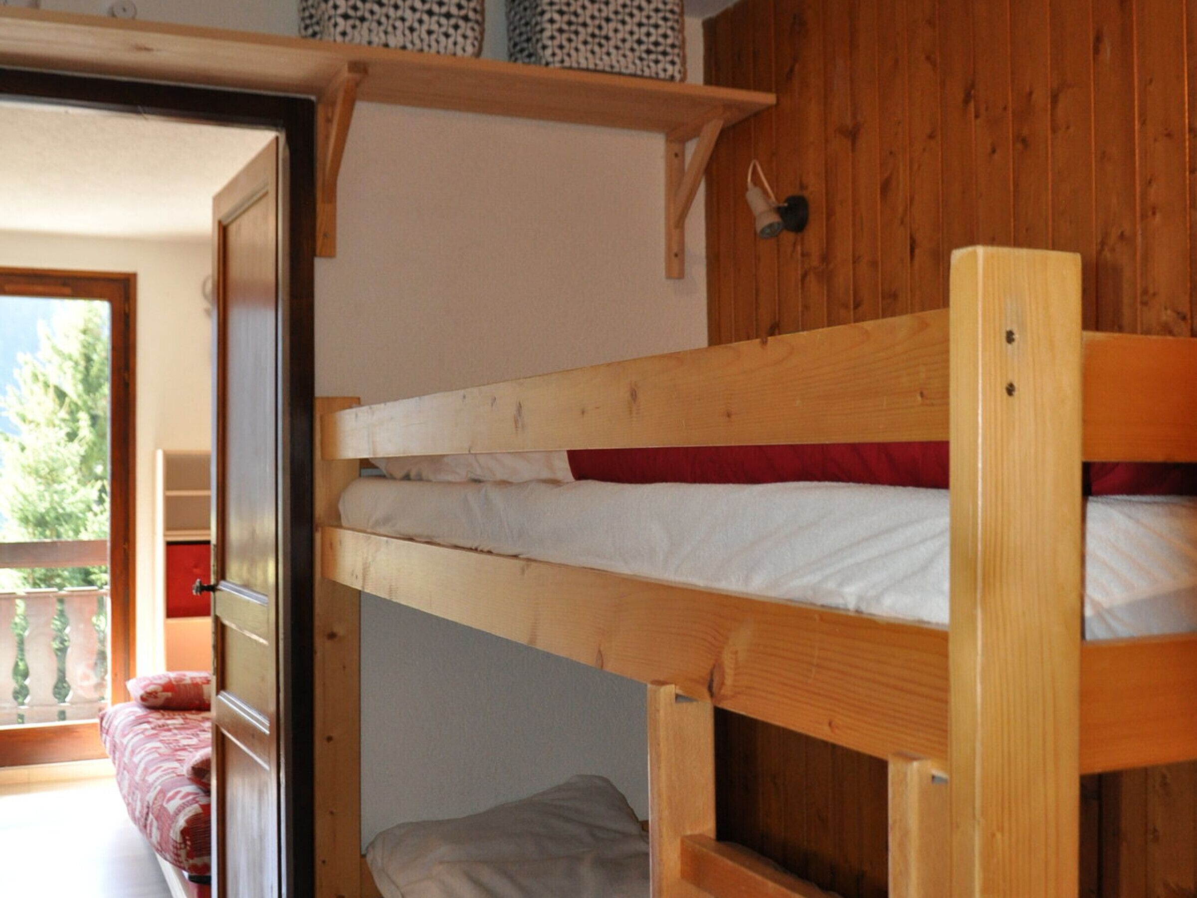 Una cama litera con cabecera de madera y repisa superior.