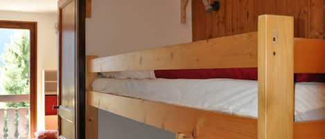 Una cama litera con cabecera de madera y repisa superior.
