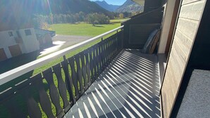 A balcony with a view of a green field and mountains.