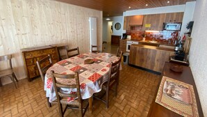 A dining area with a wooden table and chairs, a kitchen with a microwave, and a wooden ceiling.