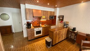 A compact kitchen with wooden cabinets, a microwave, a coffee maker, and a trash bin.