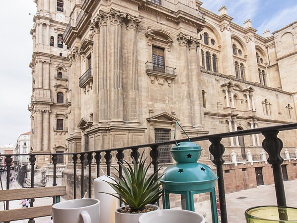 A balcony with a view of a historic building with columns and arches.