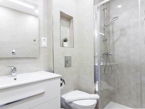 A modern bathroom with a glass-enclosed shower, a white sink, and a toilet.