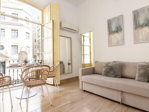 A modern living room with a sofa, chairs, a dining table, and artwork on the walls.