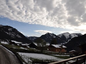 Un village de montagne avec des maisons en bois, un pont en bois et des montagnes enneigées.