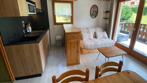 Eine kompakte Küche mit Holzschränken, einer Mikrowelle und einer kleinen Essecke mit Tisch und Stühlen.