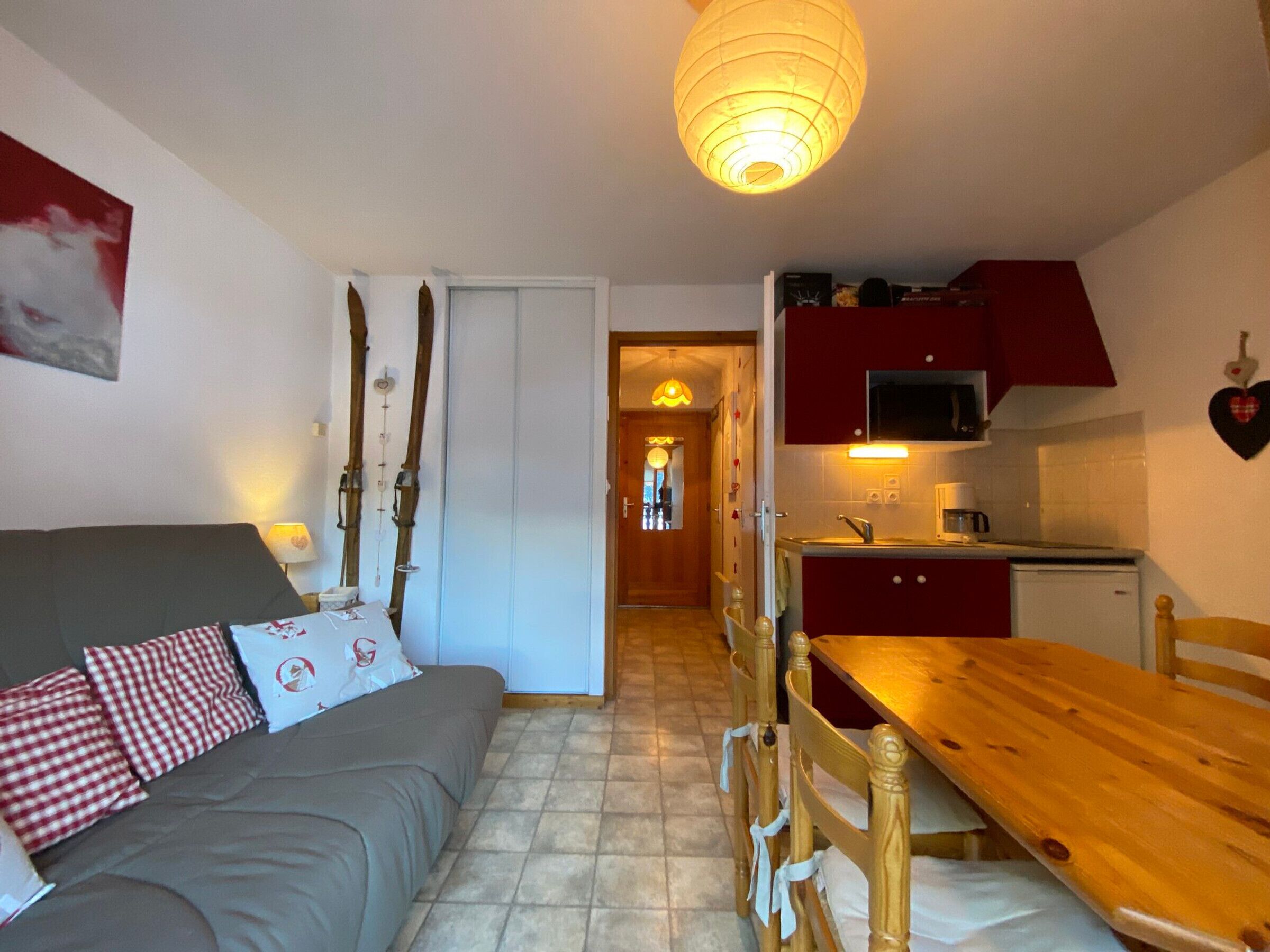 Ett kompakt bostadsutrymme med en soffa, ett matbord, stolar och ett litet kök.