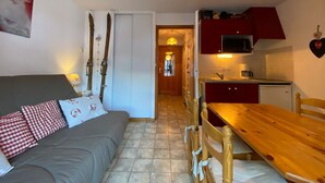 A compact living space with a sofa, dining table, chairs, and a kitchenette. - Quiet studio with balcony and parking near Châtel center (Châtel)