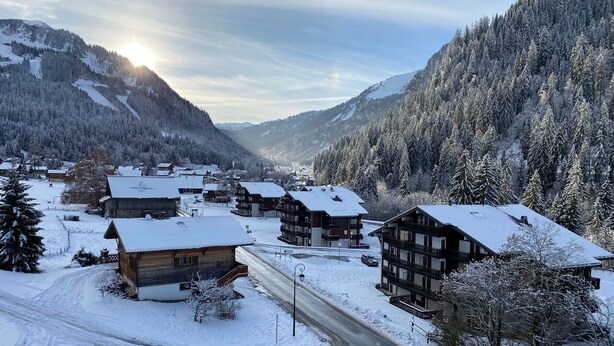 A snow-covered village with traditional wooden buildings, a winding road, and a mountain backdrop. - Quiet studio with balcony and parking near Châtel center (Châtel)