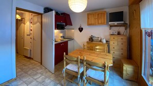 A compact kitchen with a dining area, wooden cabinets, a microwave, and a television. - Quiet studio with balcony and parking near Châtel center (Châtel)