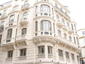 Un edificio histórico con detalles arquitectónicos ornamentales, varios balcones y ventanas amplias.