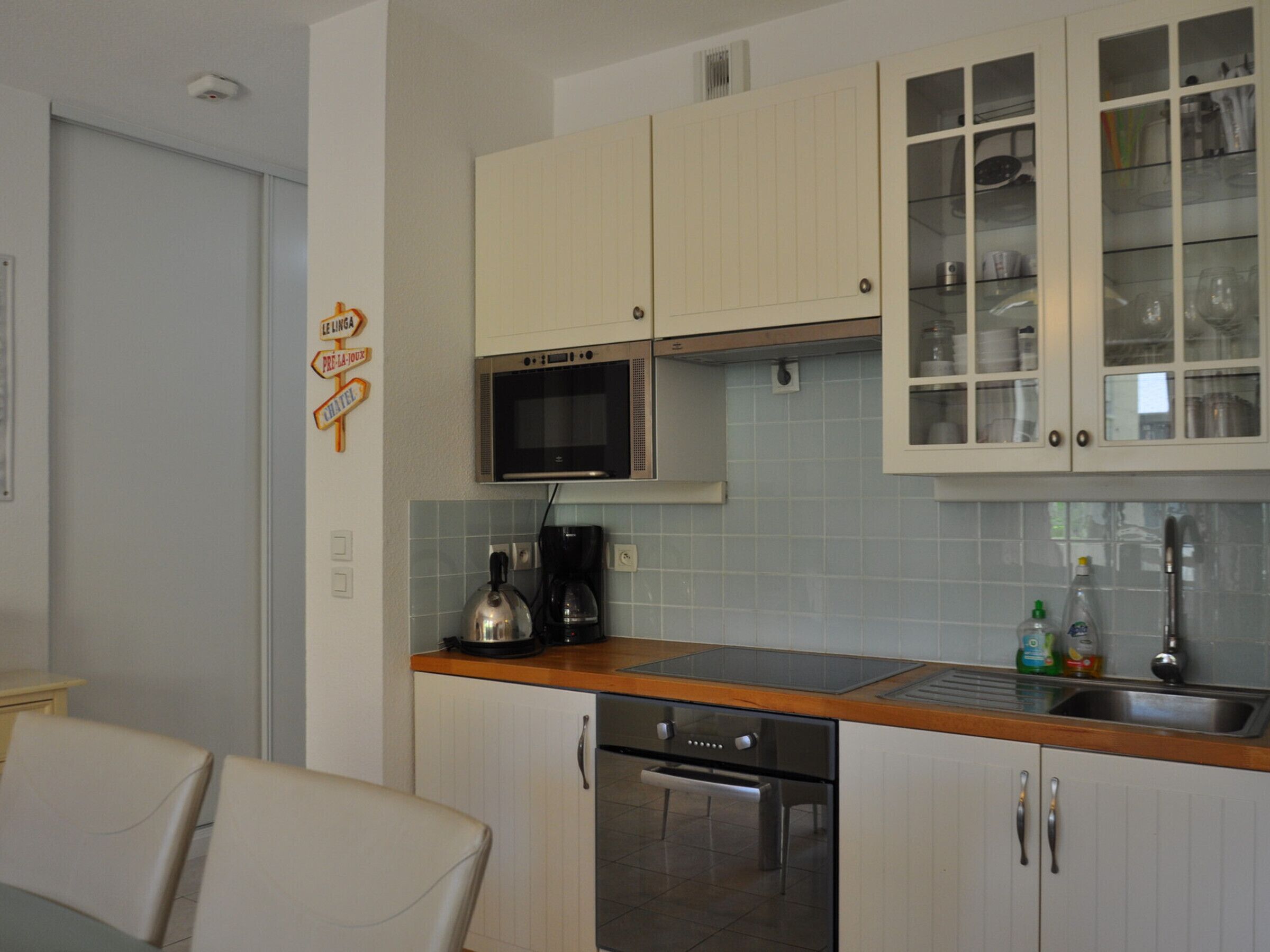 A kitchen with white cabinets, a microwave, a stove, and a sink.