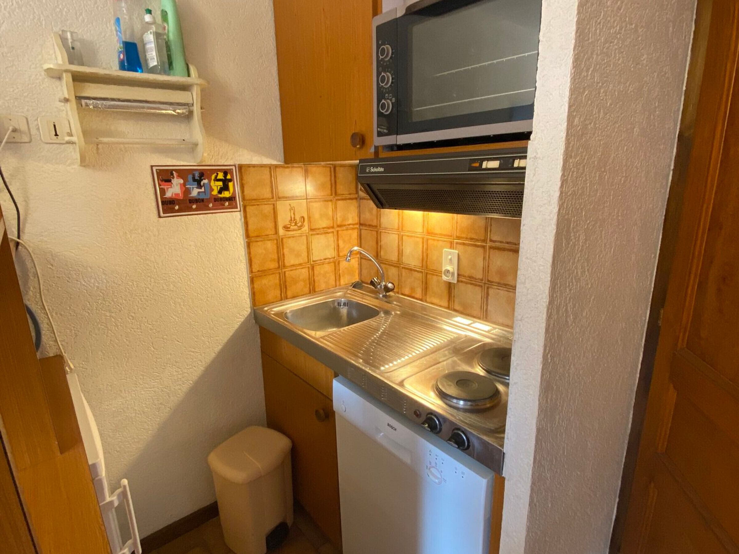 A compact kitchen with a Bosch dishwasher, a microwave, and a sink.