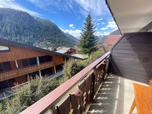 Un balcon offrant une vue sur une chaîne de montagnes boisée et un ciel dégagé.
