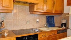 A kitchen with wooden cabinets, a dishwasher, a coffee maker, and a blue drying rack. - Spacious apartment in Châtel with sunny terrace (Châtel)