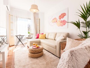 A modern living room with a sofa, a round coffee table with drinks, a fluffy white pouf, and a large plant. - Bright 1-bedroom apartment in Málaga center (Málaga)