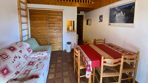 A cozy room with a wooden ceiling, a loft bed, a dining table with chairs, and a sofa. - Cozy apartment near the center, pets allowed (Châtel)