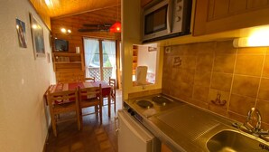 A compact kitchen with a microwave, sink, and a dining area with a table and chairs. - Cozy apartment near the center, pets allowed (Châtel)