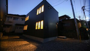 Um edifício moderno de dois andares com várias janelas e um caminho de acesso de cascalho.