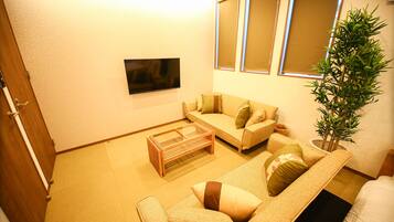 Una sala de estar acogedora con un sofá, una mesita de centro y un televisor en la pared.