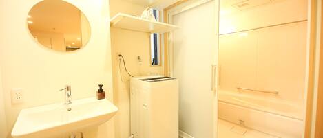A bathroom with a sink, mirror, and a white appliance, possibly a heater or dryer, next to a closet.