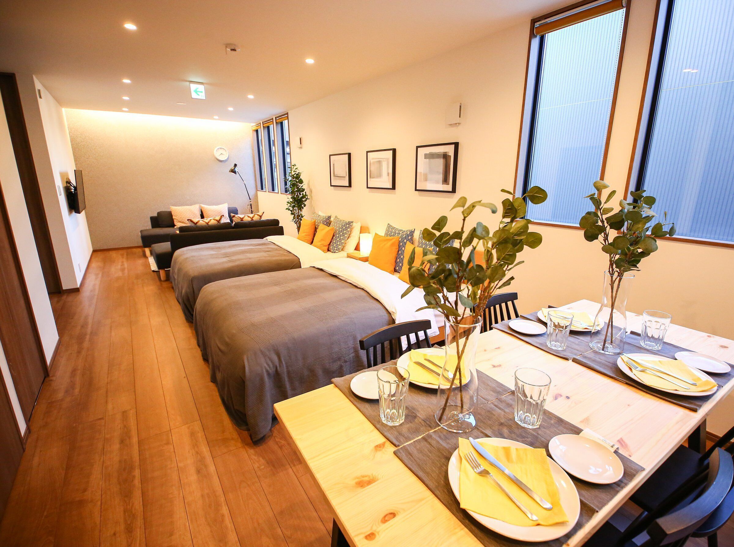 Habitación de hotel con comedor, dos camas, un sofá y una mesa de comedor para dos personas.
