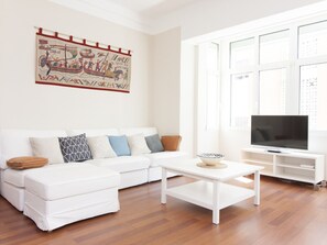 A modern living room with a white sofa, a coffee table, and a flat-screen TV. - Charming Apartment in Málaga's Historic Center - Near Museums, Shops, and Attractions (Málaga)