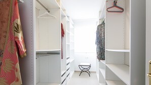 A narrow walk-in closet with white shelving, a hanging rack, and a small stool. - Bright 2-Bedroom Apartment Near Beach and Train Station in Central Málaga (Málaga)