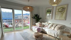 A spacious living room with a large sliding glass door leading to a balcony, a white sofa, a coffee table, and a large plant. - Bright 2-Bedroom Apartment Near Beach and Train Station in Central Málaga (Málaga)