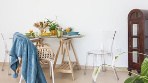 A room with a dining table set with dishes, a chair, a blue towel, and a potted plant. - Bright 2-Bedroom Apartment Near Beach and Train Station in Central Málaga (Málaga)
