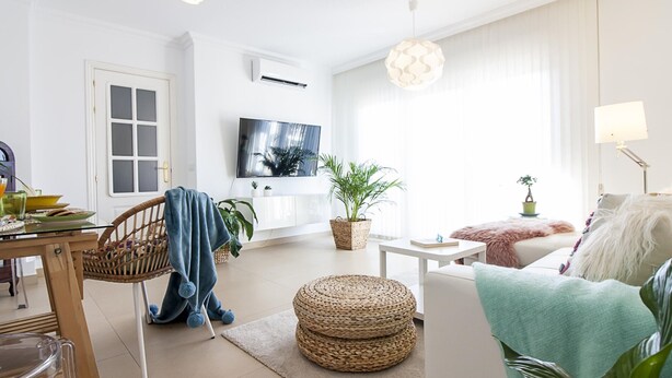 A modern living room with a TV, wicker furniture, and a large window. - Bright 2-Bedroom Apartment Near Beach and Train Station in Central Málaga (Málaga)