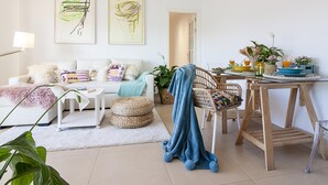 A modern living room with a white sofa, a dining table with chairs, and artwork on the walls. - Bright 2-Bedroom Apartment Near Beach and Train Station in Central Málaga (Málaga)