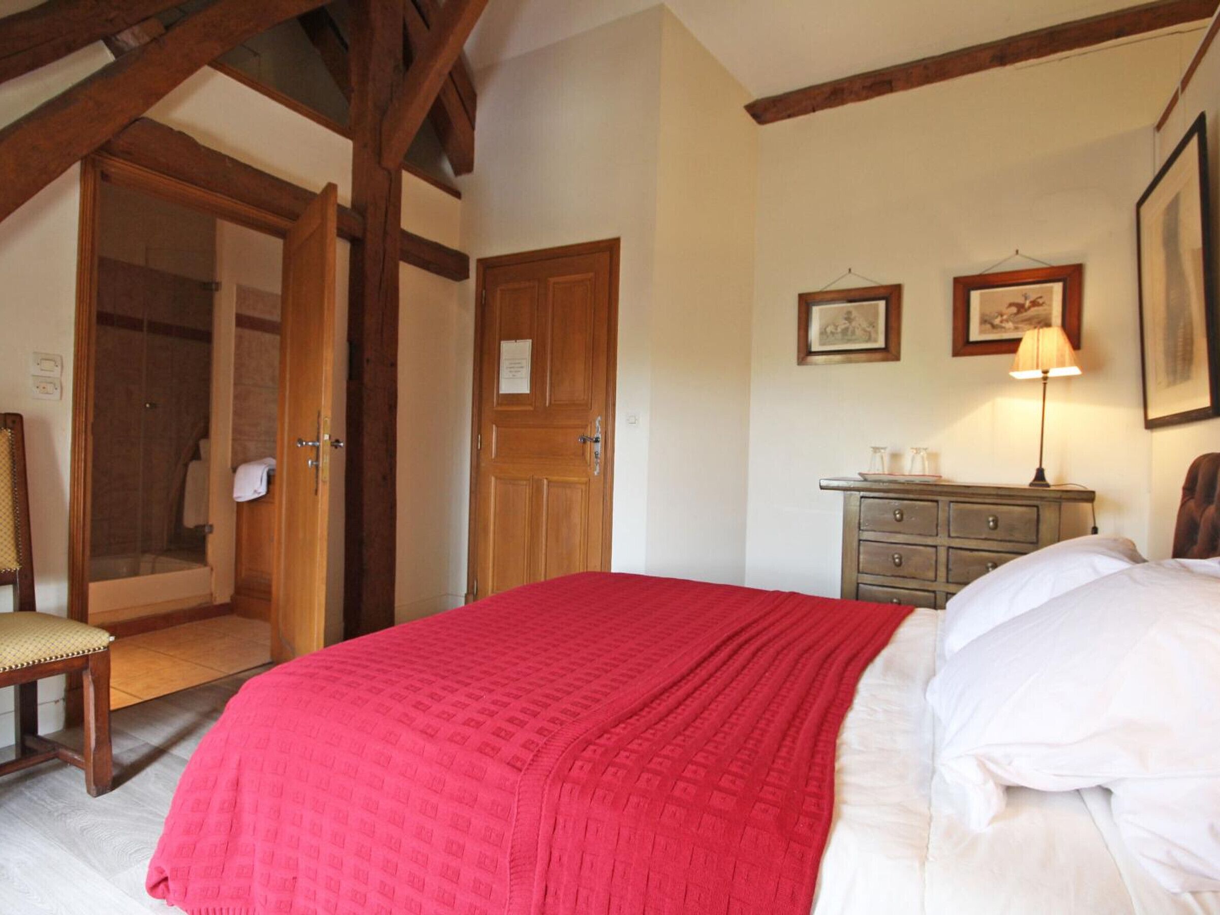 A bedroom with a bed, a wooden door, a chair, a dresser, and a framed picture on the wall.